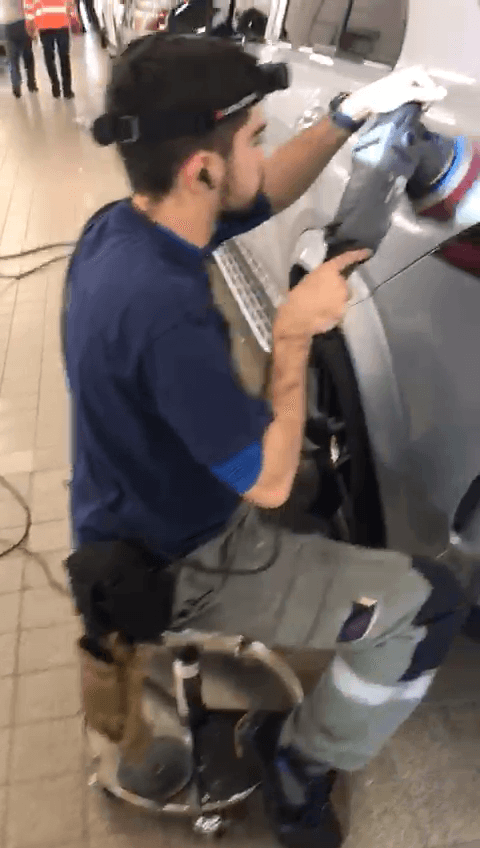Original video frame: a technician polishing a vehicle